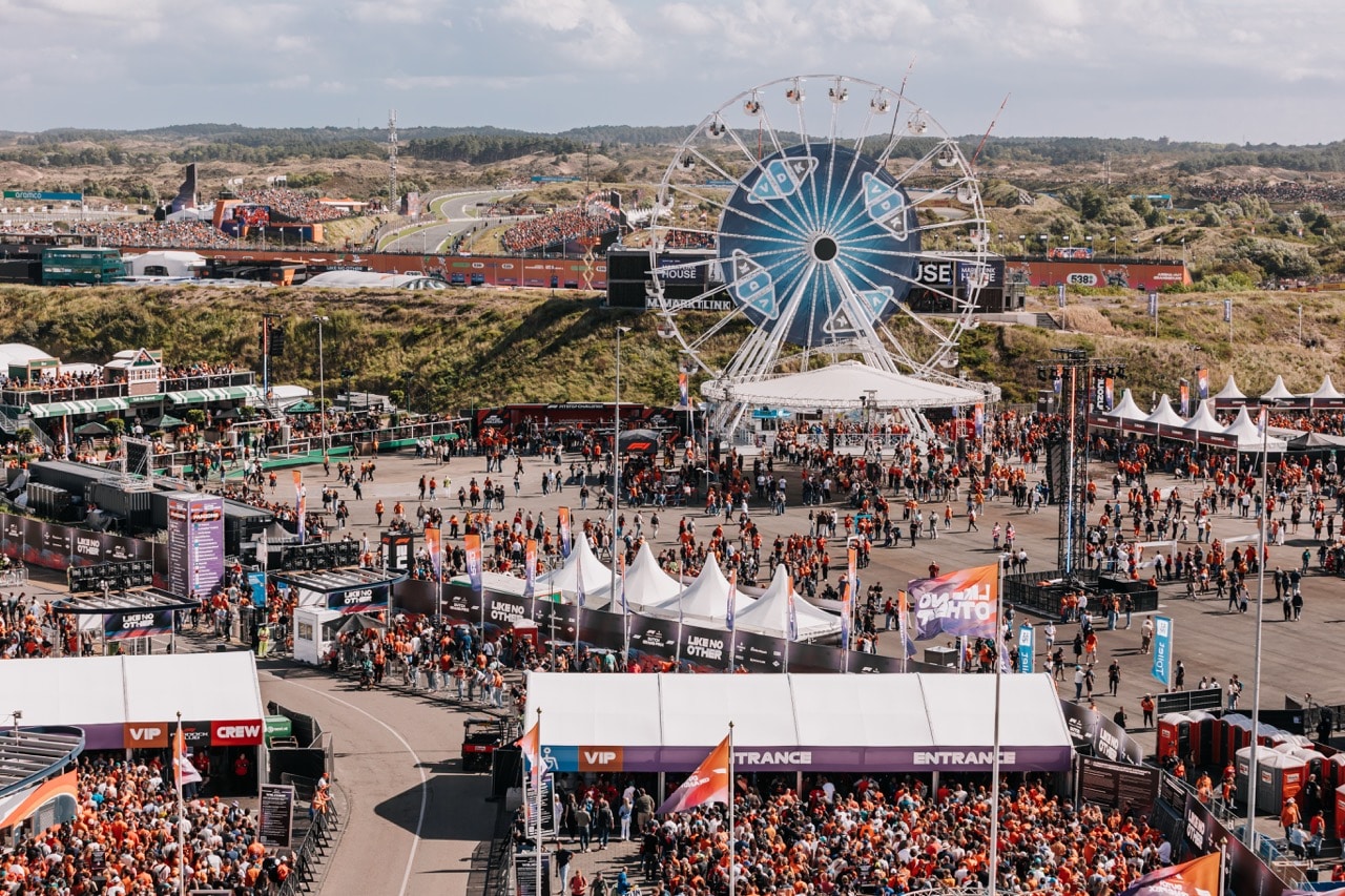 Circuit zandvoort tijdens de dutch grand prix vanaf boven met alle fans in oranje en het reuzenrad op het terrein.